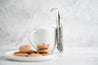 Tea Infuser standing up against a white cup with cookies in foreground