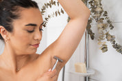 Silver Safety Razor in a shower held by a woman shaving her arm pit