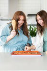 Two women with granola on a reusable Baking Mat 