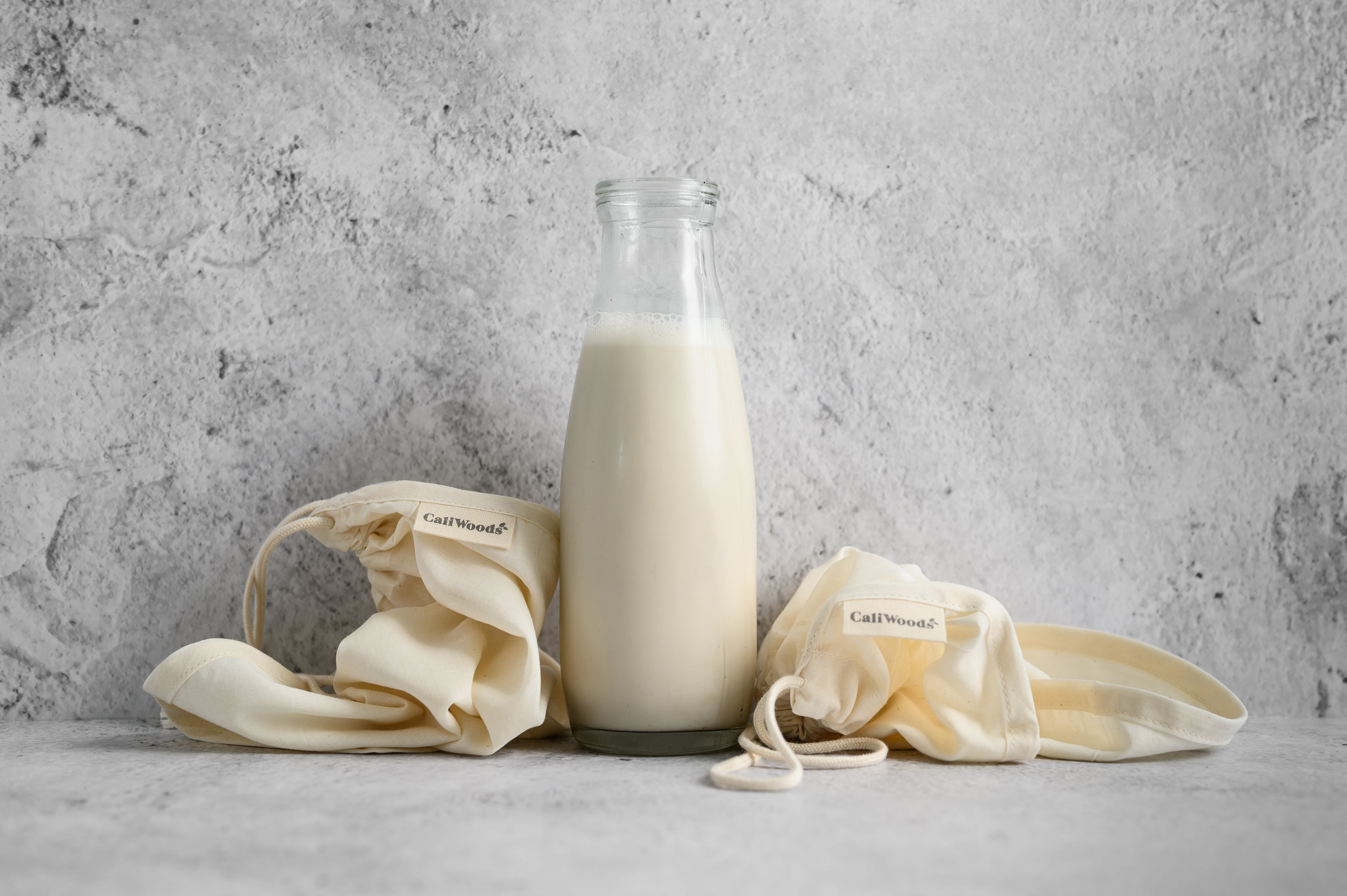 CaliWoods Nut Mylk bag next to glass bottle of nut milk