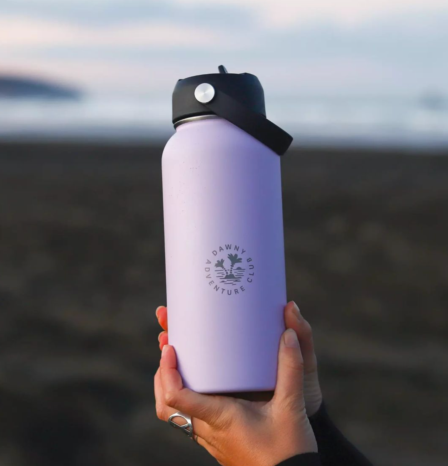 950ML Purple stainless steel water bottle being held in hands on a beach