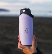 950ML Purple stainless steel water bottle being held in hands on a beach