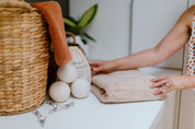 CaliWoods Dryer Balls on a bench with Stainless Steel Pegs and the hands of a woman on a towel