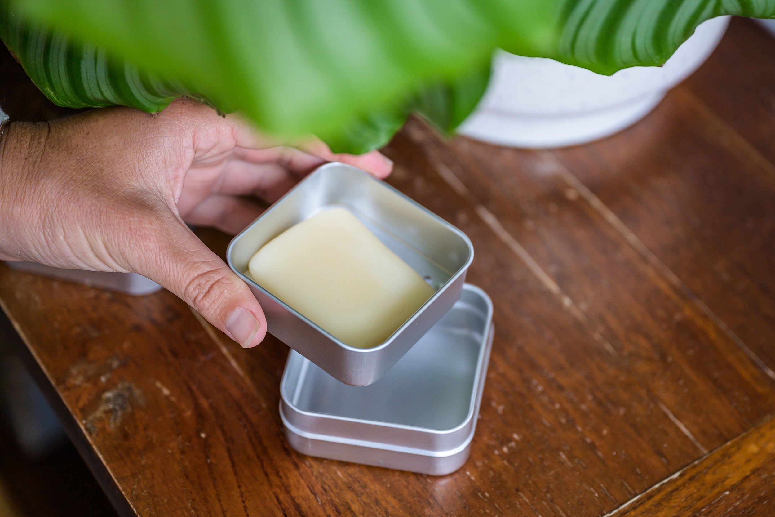 Hand holding a travel Soap Box with the middle drainage layer showing and soap bar on top.