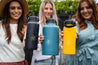 Three women holding out insulated water bottles in their hands