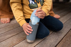 Boy holding a water bottle on the deck opening the lid