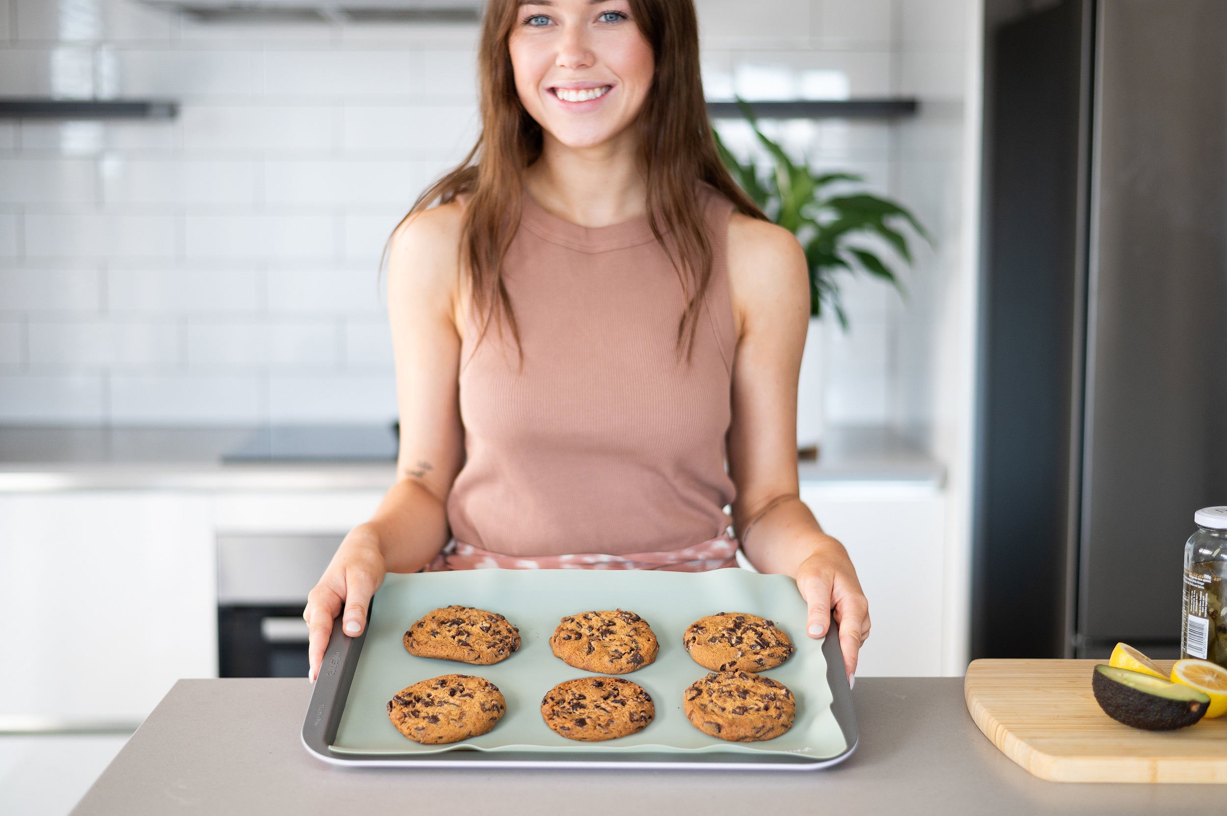 Green Reusable Baking Mat on a tray with cookies and woman smiling