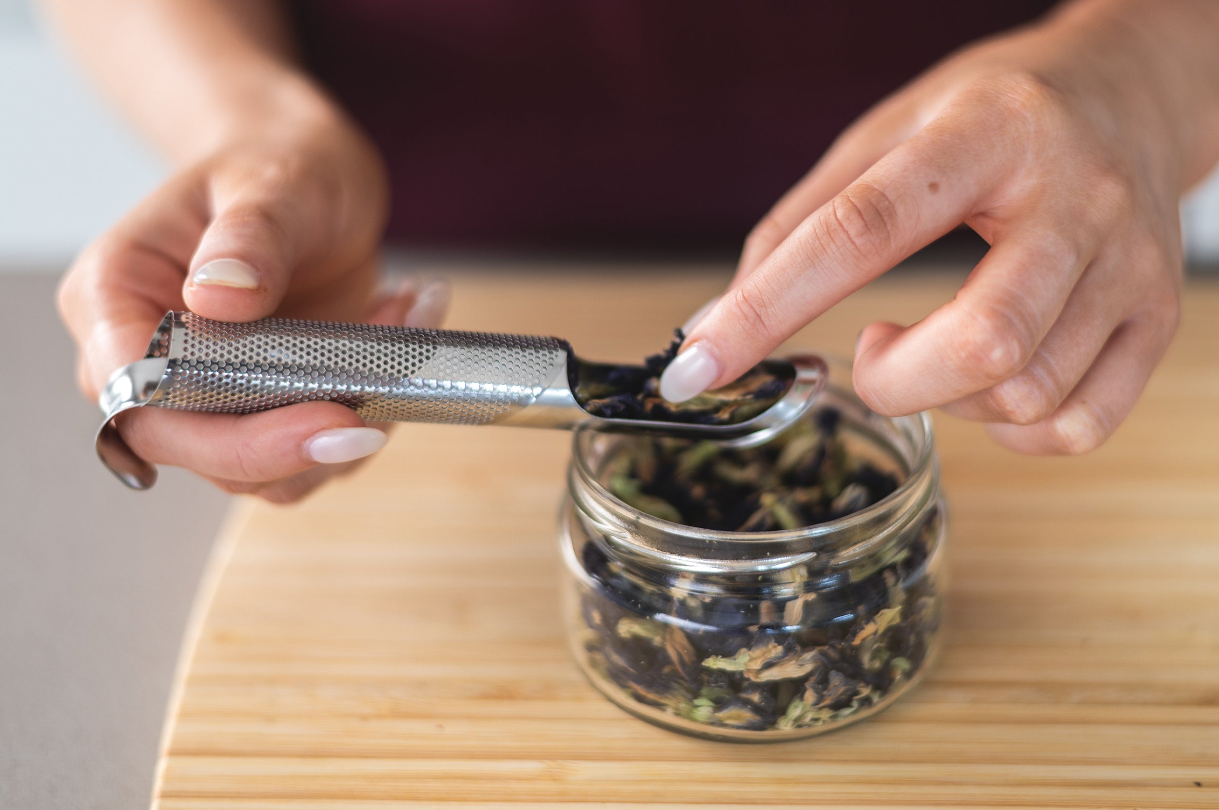 Finger placing loose leaf tea into the CaliWoods tea infuser