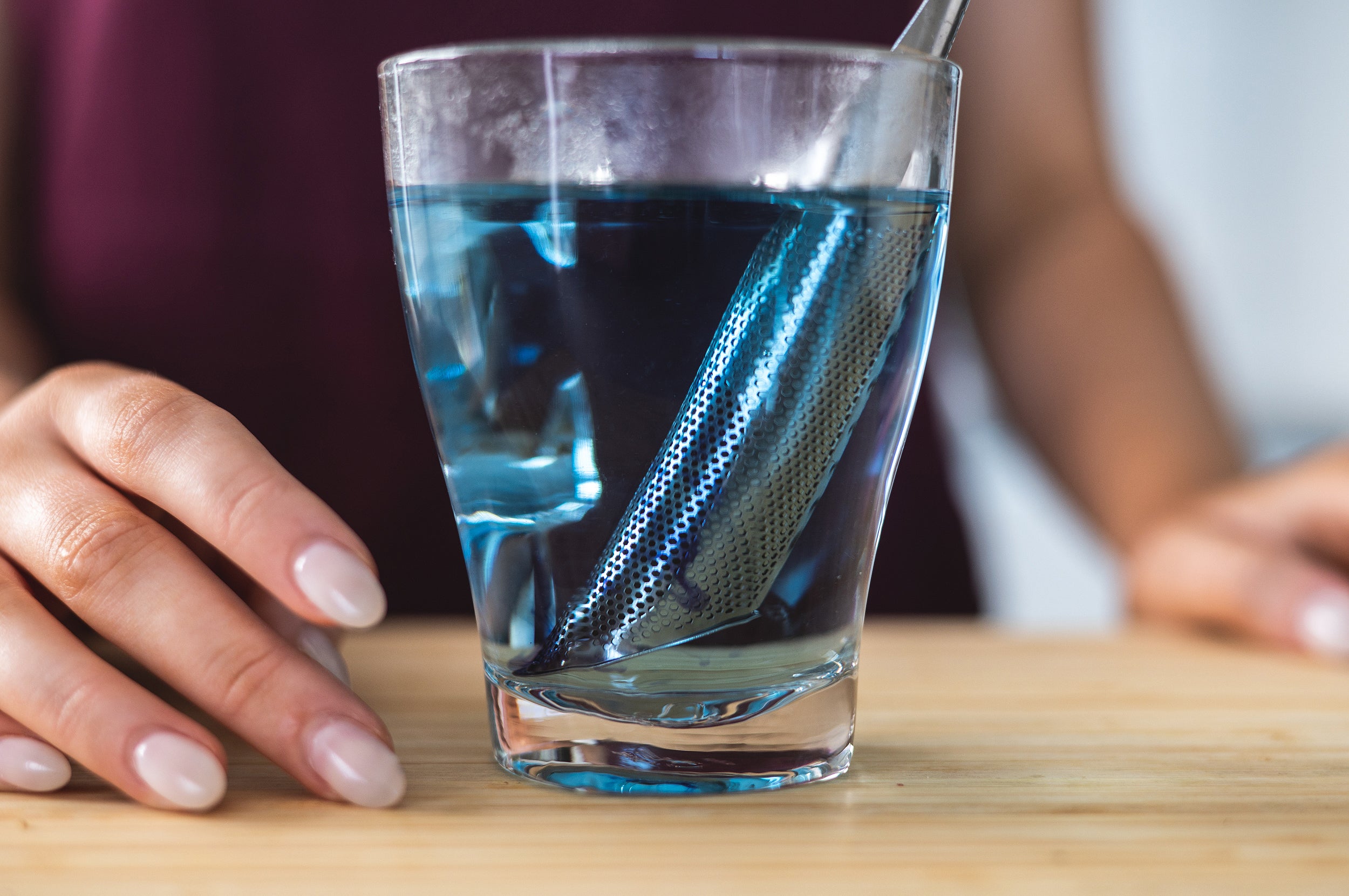 Close up of cup with the CaliWoods Tea Infuser straining blue tea