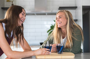 two women laughing over a cup of tea with each cup showing the tea infusers