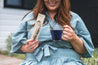 Woman holding the Tea Infuser in the packaging and then a cup of blue tea in the other hand