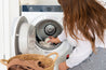 Woman placing a Dryer Ball into laundry in a Dryer