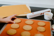 Orange silicone baking mats with cookies on top 